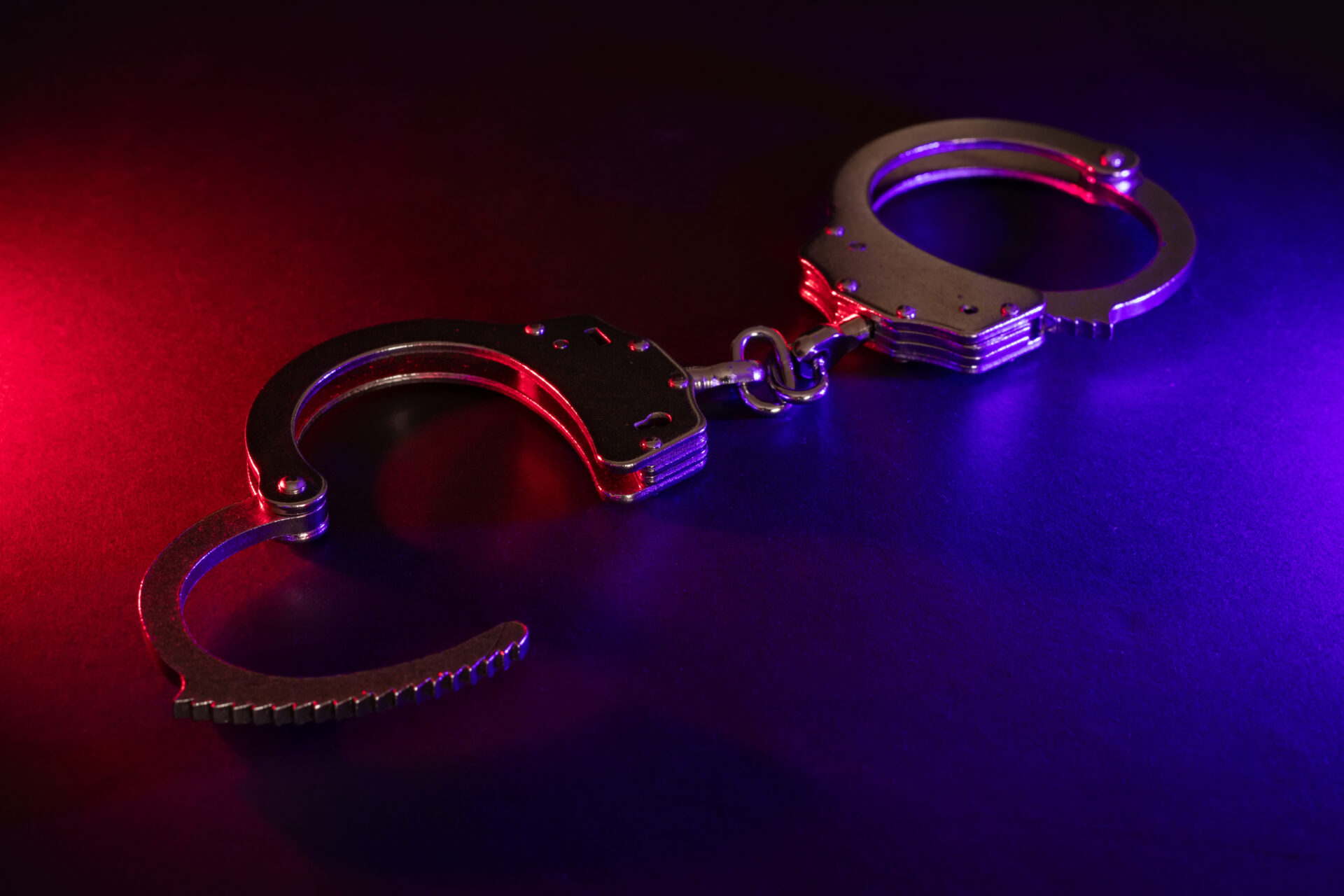 Closed handcuffs on the street pavement at night with police car lights high contrast image
